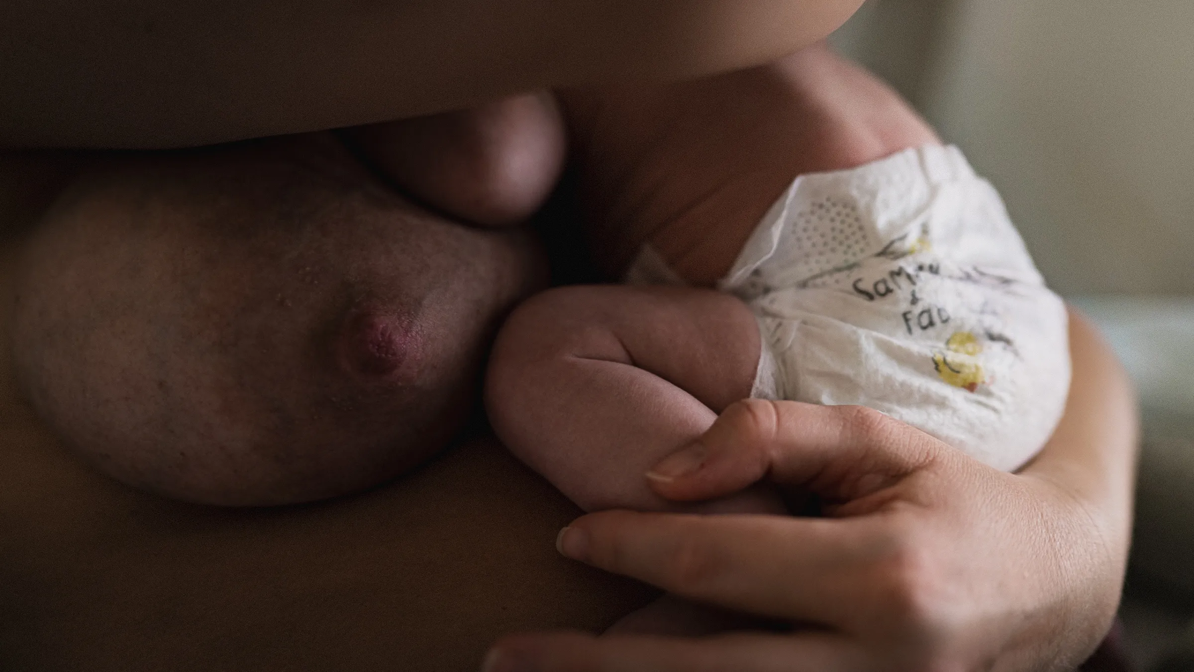 Säugling liegt in Windel auf dem Bauch einer erwachsenen Person